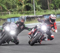 two people riding motorcycles on a track