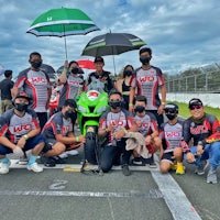 a group of people posing with umbrellas on a race track