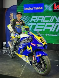 a man posing on a blue and yellow motorcycle