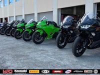 a row of green and black motorcycles parked in front of a building