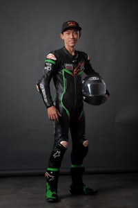 a man in a black and green motorcycle suit posing for a photo